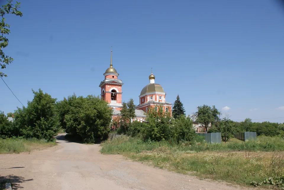 Летний вид на Покровскую церковь издалека, грунтовая дорога на переднем плане