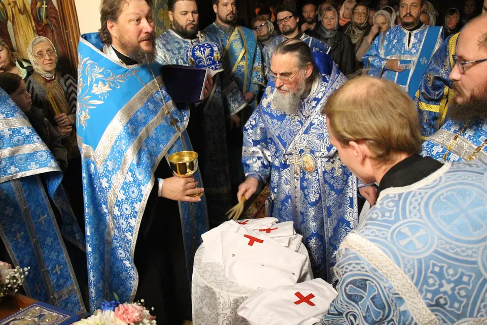 Священник возлагает облачение на коленопреклонённую сестру милосердия в храме