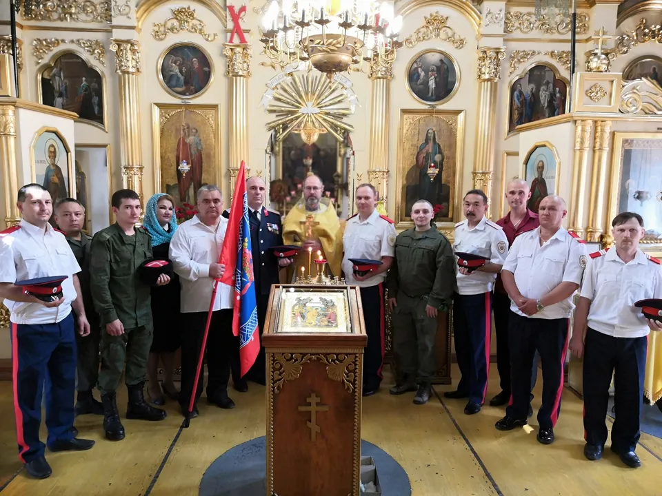 Казаки в форме с флагами стоят в храме во время принятия присяги