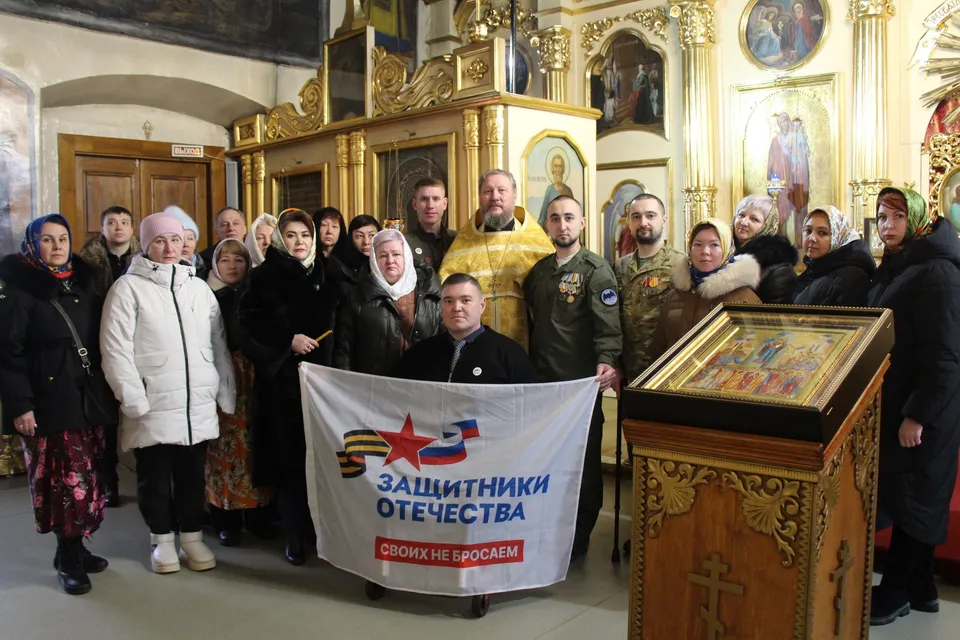 Прихожане и клирик Покровского храма с баннером фонда «Защитники Отечества» на молебне