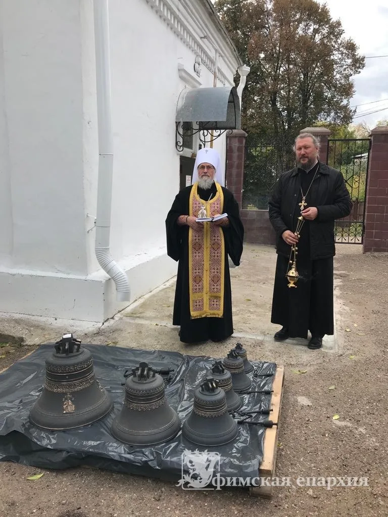 Митрополит и клирик у ряда новых колоколов, разложенных на земле перед храмом